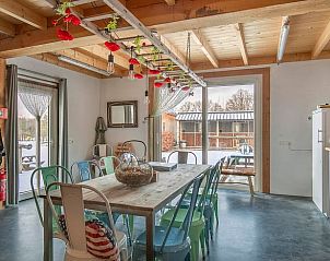 Gezellige eetruimte in Huisje in Eersel, vakantiewoning in de Kempen, Noord Brabant, met kleurrijke stoelen en houten tafel.
