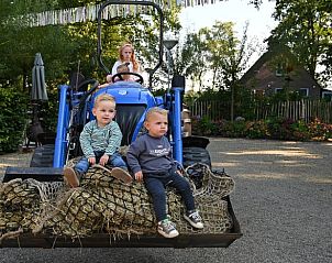 Kinderen op tractor in de tuin van Huisje in Eersel, een vakantiehuis in de Kempen, Noord Brabant.