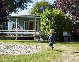Kind speelt voor VerandaChalet in Eersel, Noord Brabant, met zonnige veranda en groene tuin, ideale vakantiehuisomgeving in de Kempen.