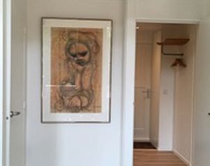 Binnenruimte van Vakantiehuisje in Eersel, Kempen, Noord Brabant met kunst aan de muur en een open deur naar de gang.