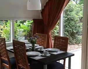 Gezellige eetkamer in Vakantiehuisje in Eersel, Noord Brabant met uitzicht op de groene tuin, ideaal voor een ontspannen verblijf.