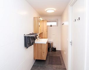 Modernes Badezimmer im Ferienhaus in Hapert, gelegen in der Region Kempen, Nordbrabant, mit schlichten Holzmbeln und frischen weien Fliesen.