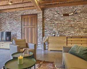 Gezellige woonkamer in De Rouwenbogt vakantiehuis Reusel met rustieke stenen muur.