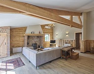 Gezellige zithoek met open haard in De Hoeve III, vakantiehuis in Hulsel, omgeven door rustieke houten wanden in de Kempen.