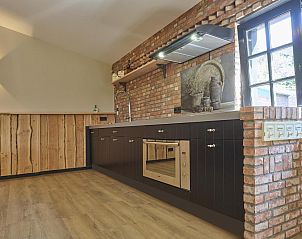 Moderne keuken in De Hoeve III, vakantiehuis in Hulsel, met bakstenen muur en houten afwerking in de Kempen, Noord Brabant.