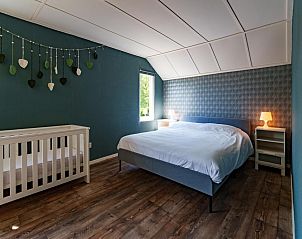 Ruime slaapkamer met babybed in Achter de Vijf Linden, vakantiehuis in Knegsel, Noord Brabant.