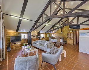 Gezellige binnenruimte van De Vrije Vogel vakantiehuis in Oisterwijk, Noord Brabant, met comfortabele zithoek en rustieke houten balken.