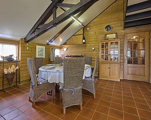 Gezellige eethoek in De Vrije Vogel, vakantiehuis in Oisterwijk, Noord Brabant, met houten interieur en comfortabele rieten stoelen.