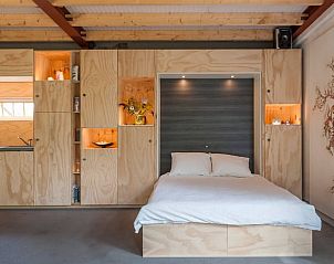 Stijlvolle slaapkamer in Vakantiehuisje in Liempde met ingebouwde houten kasten.