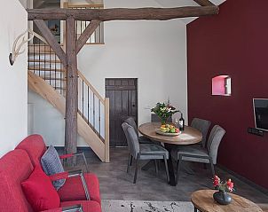 Gezellige woonkamer met rode accenten in Huisje in Kaatsheuvel, perfect voor familiebijeenkomsten.