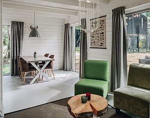 Sfeervolle slaapkamer in vakantiehuis Patio 4, Schaijk, Noordoost Brabant, met uitzicht op groene natuur door grote ramen.