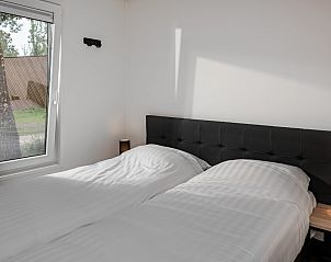 Gezellige slaapkamer in Forest Cabin Pets 6, een vakantiehuis in Schaijk, Noordoost Brabant, met uitzicht op de natuur door het raam.