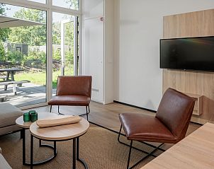 Lichte woonkamer van Forest Cabin 6, vakantiehuis in Schaijk, Noordoost Brabant, met uitzicht op het groene terras en moderne meubels.