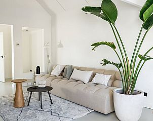 Gezellige zithoek in Vakantiehuisje in Beers, Noord Brabant, met comfortabele bank en groene planten.