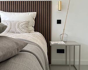 Slaapkamerdetails in Vakantiehuisje in Beers, Noordoost Brabant met houten bedframe en zachte kussens.