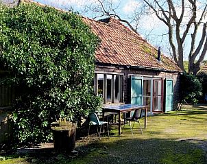 Vakantiehuisje in Huisseling, Noord-Brabant, terras met houten tafel en stoelen omgeven door groen.