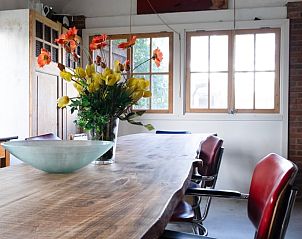 Vakantiehuisje in Huisseling, Noord-Brabant, eetkamer met bloemen op tafel en uitzicht op de tuin.