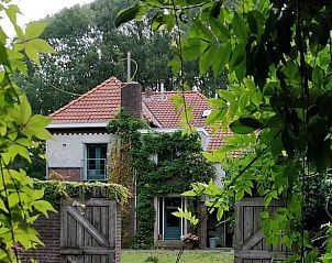 Vakantiehuisje in Huisseling, Noord-Brabant, huis omgeven door weelderig groen en houten poorten.