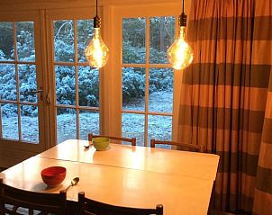 Gezellige eetkamer in Vakantiehuis in Bergen op Zoom met uitzicht op winterse tuin.