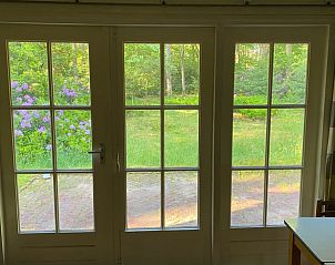 Uitzicht vanuit de woonkamer van Vakantiehuis in Bergen op Zoom op groene tuin.