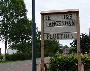 Ingang van Vakantiehuisje in Waspik, West Brabant, met bord en groene omgeving.
