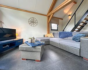 Comfortabele zithoek in Onirico vakantiehuis, Alphen, Noord Brabant, met stijlvolle meubels en trap naar bovenverdieping.