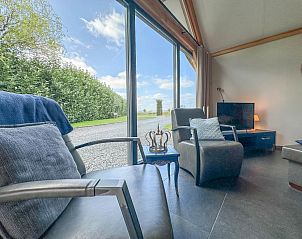 Uitzicht vanuit de woonkamer van Onirico in Alphen, Noord Brabant, met grote ramen en groene omgeving.