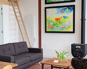 Knusse woonkamer in Vakantiehuisje in Gilze, West Brabant, met kleurrijke kunst.