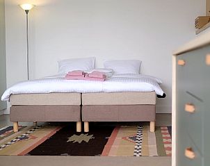 Comfortabel bed in Vakantiehuisje in Gilze, Noord Brabant, met kleurrijk tapijt.