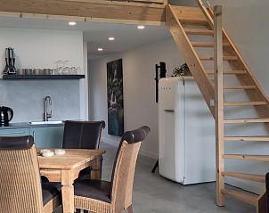 Cozy indoor area of Huisje in Rucphen, vacation home in West Brabant, with wooden staircase, modern kitchen and dining area.