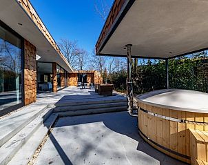 Buitenterras met hottub in Vakantiehuisje in Oosterhout, Noord Brabant, omgeven door groen.