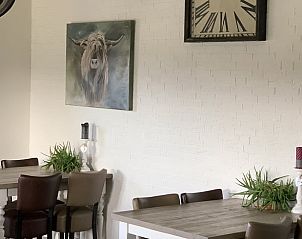 Gezellige eetkamer in Vakantiehuis in Terheijden, West Brabant met kunst en klok, ideaal voor een ontspannen verblijf in Noord Brabant.