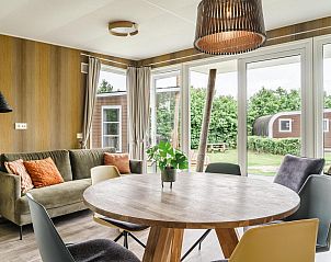 Gezellige woonkamer in Strandhuisje voor 5 personen, Julianadorp, Noordzeekust, met uitzicht op groene tuin en comfortabele zithoek.