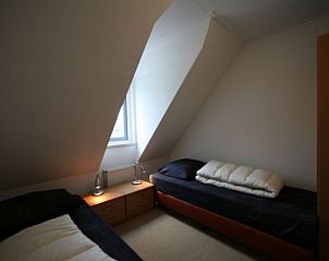 Sfeervolle slaapkamer van Bungalow met sauna in Julianadorp, Noordzeekust, Noord-Holland, met knusse bedden onder een schuin dak.