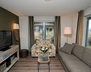 Gezellige woonkamer van 8 pers. luxe villa met sauna in Julianadorp, Noordzeekust. Comfortabele zitruimte met uitzicht op de tuin.