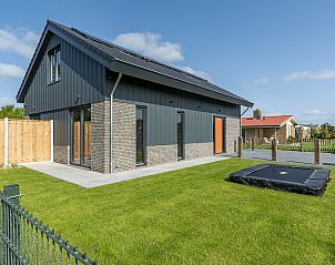 Zijaanzicht van Wellness Villa Lotje, vakantiehuis in Julianadorp met groene tuin en trampoline.