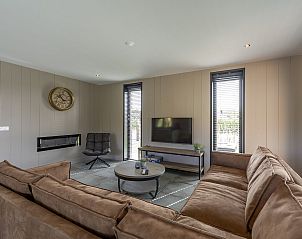 Gezellige zithoek in Wellness Villa Lotje, vakantiehuis in Julianadorp, met flatscreen-tv en open haard.