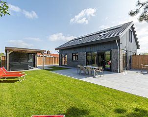 Achtertuin van Wellness Villa Lotje in Julianadorp, met terras en ligstoelen voor ontspanning.