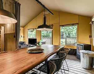 Stijlvolle eetkamer in Strandtent 8 personen, Julianadorp, met uitzicht op het terras en groene omgeving.