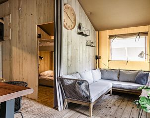 Lichte woonkamer in Strandtent 8 personen, Julianadorp, met comfortabele bank en houten accenten.