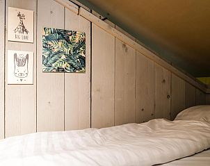 Gezellige binnenruimte van Strandtent 6 personen in Julianadorp, Noordzeekust. Houten interieur met decoratieve kunst aan de muur.