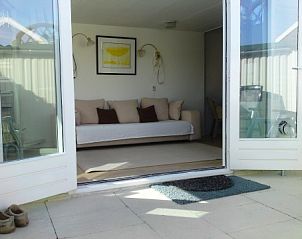 Zonnig terras van zomerhuis DEZEESTER, Egmond aan Zee, met toegang tot een gezellige zithoek binnen.