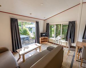 Gezellige woonkamer van Kinderchalet 6 in Egmond aan Zee, Noordzeekust, Noord-Holland met uitzicht op terras en groene omgeving.