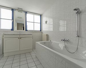 Spacious bathroom with bath in Buitenplaats 100 Callantsoog vacation home in North Holland, perfect for relaxation.