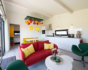 Gezellige woonkamer van Tulip Mania 4 vakantiehuis in Callantsoog, Noord-Holland, met kleurrijk interieur en moderne keuken aan de Noordzeekust.