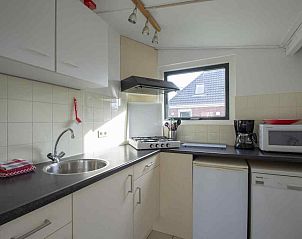 Gezellige woonkamer van vakantiehuis NH252 in Callantsoog, Noordzeekust. Licht interieur met uitzicht op de tuin, perfect voor ontspanning.