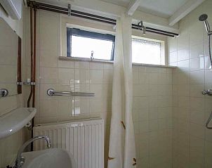 Gezellige woonkamer in vakantiehuis NH252, Callantsoog, Noordzeekust, met uitzicht op groene omgeving en comfortabele zitruimte.