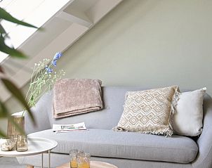 Stylish sitting area in Holiday home in Callantsoog, North Sea coast, North Holland with gray sofa and wooden table.