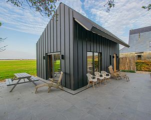 Terrace of vacation home Spoelde wiel in Callantsoog, North Sea coast overlooking green fields.