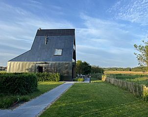 Side view of De Bonte Specht vacation home with green garden in Callantsoog, North Holland.